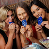 Three women holding and using iBlush Alcohol Flush Gel in a casual setting.
