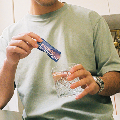 iBlush Hydration Powder sachet being poured into a drink, delivering electrolytes to support hydration and drinking recovery.