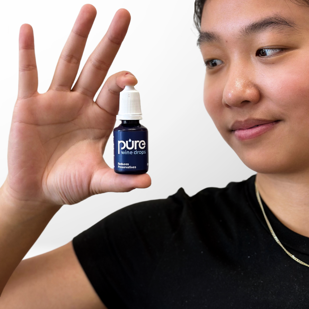 Lydia holding a PureWine drops bottle, sulfite-reducing drops designed to prevent wine-related headaches and allergic reactions.